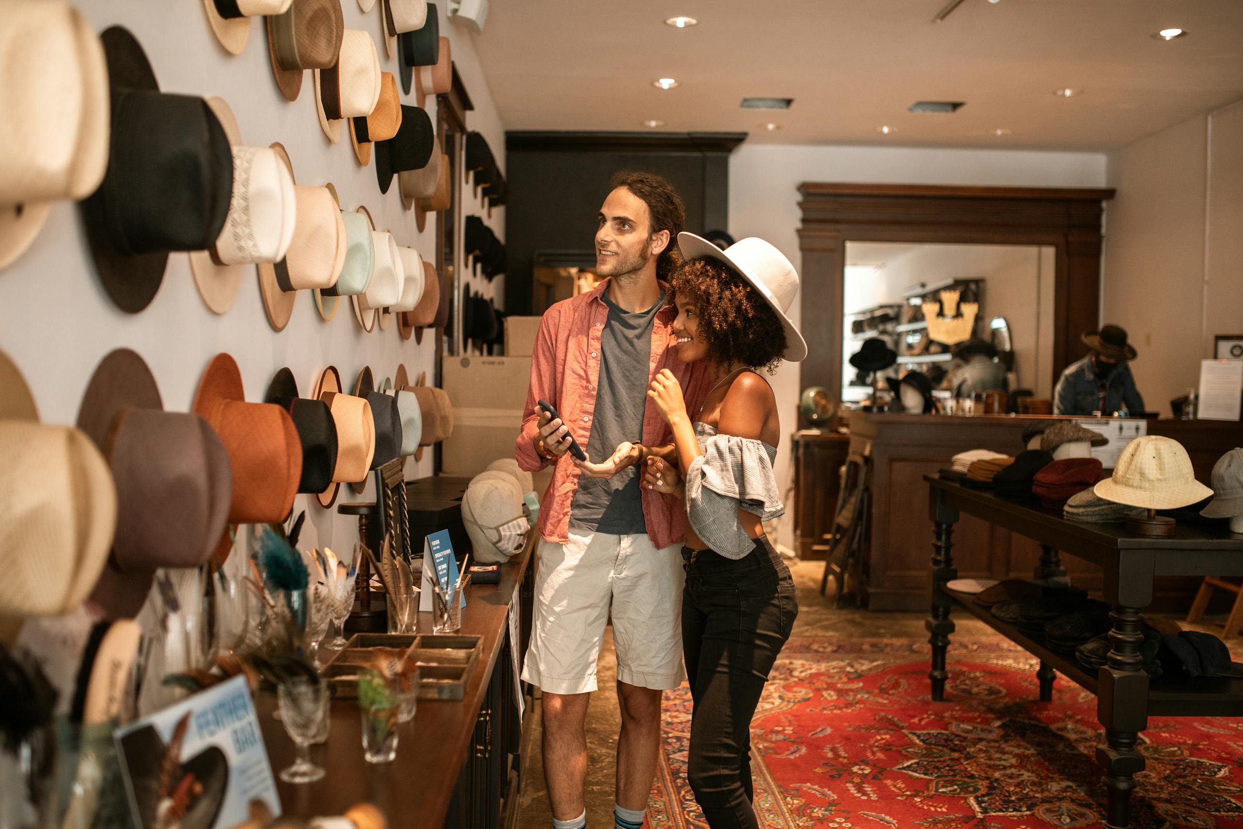 Young couple exploring a trendy hat shop, enjoying a fun shopping experience together.